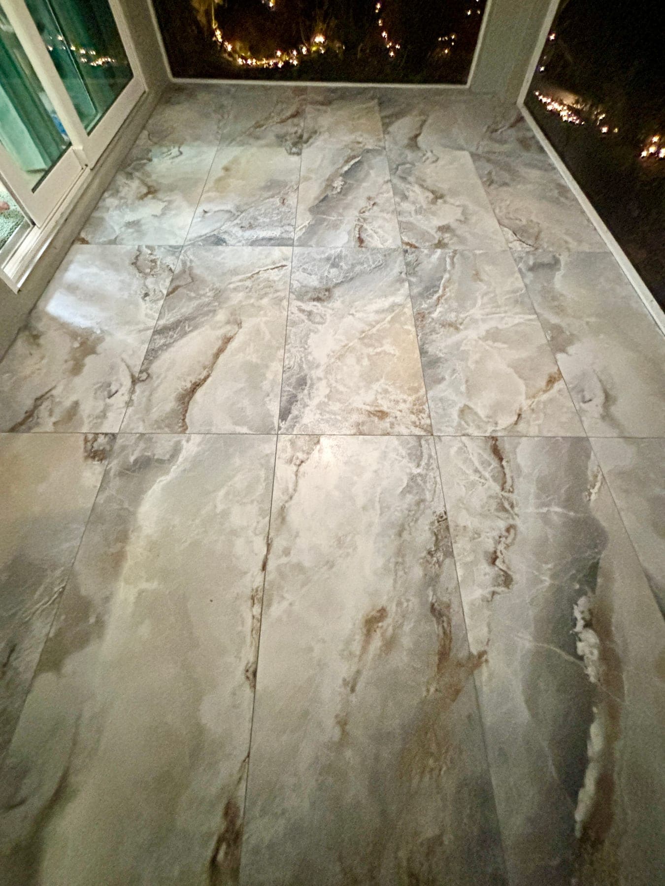 Stone-look rectangular floor tile on a screened outdoor living area