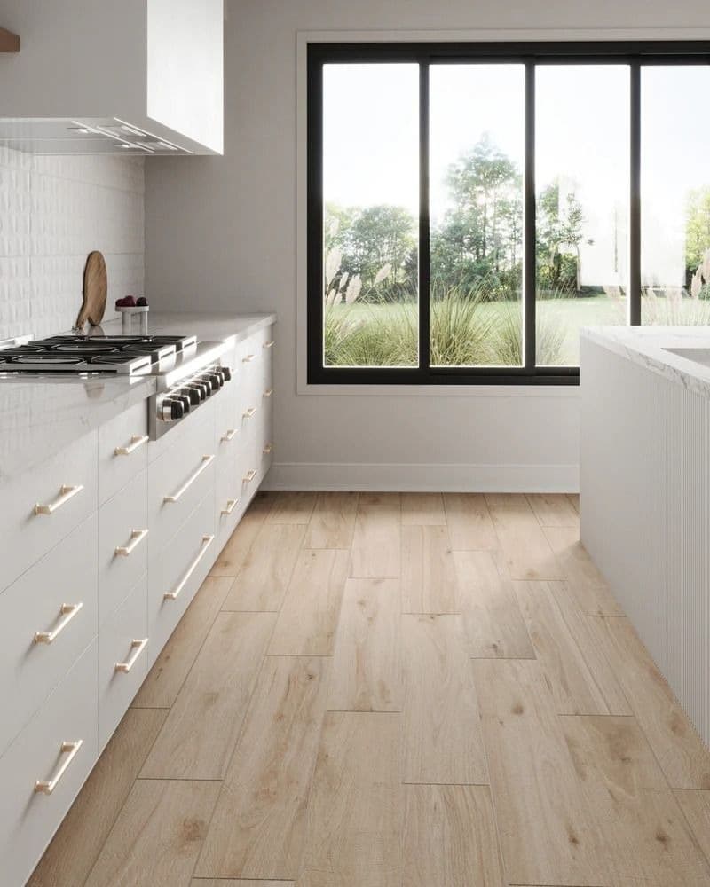 White kitchen with light wood-look plank flooring between cabinets and an island