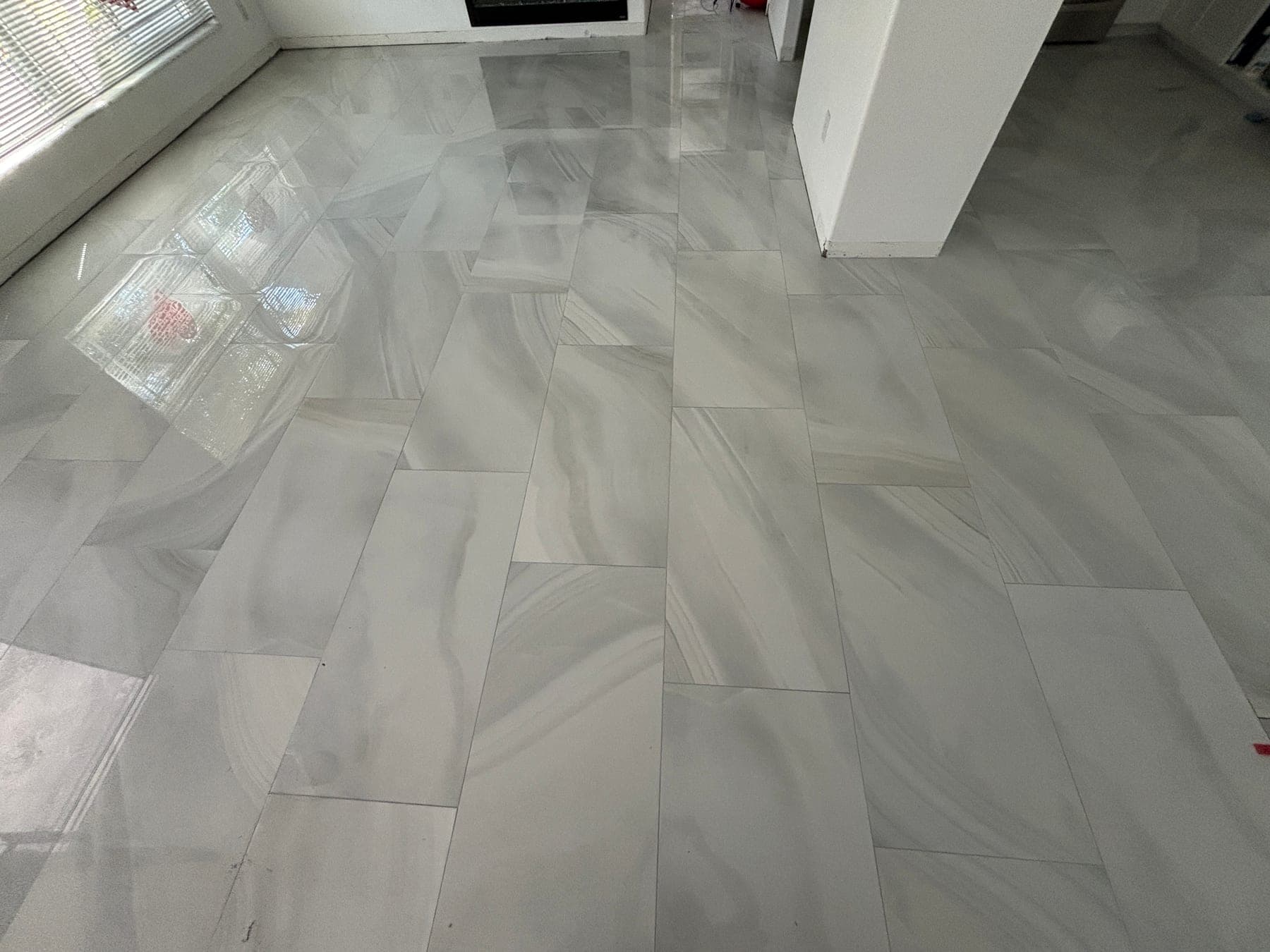 Glossy marble-look rectangular floor tile across an interior room