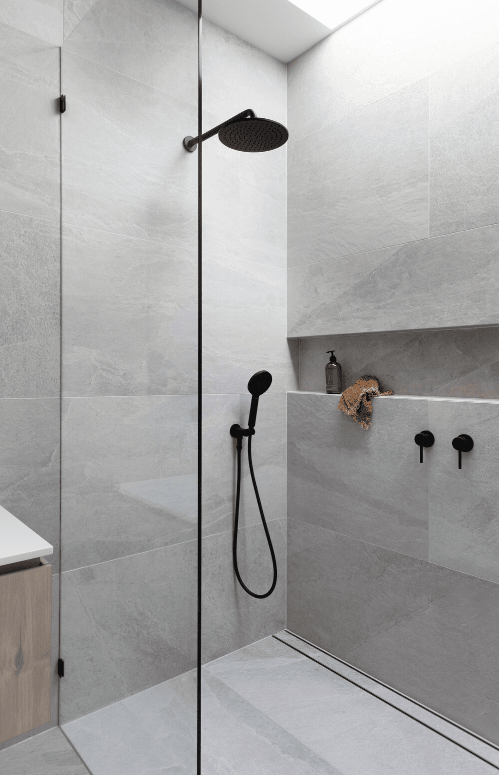 Walk-in shower finished with large-format gray wall tile