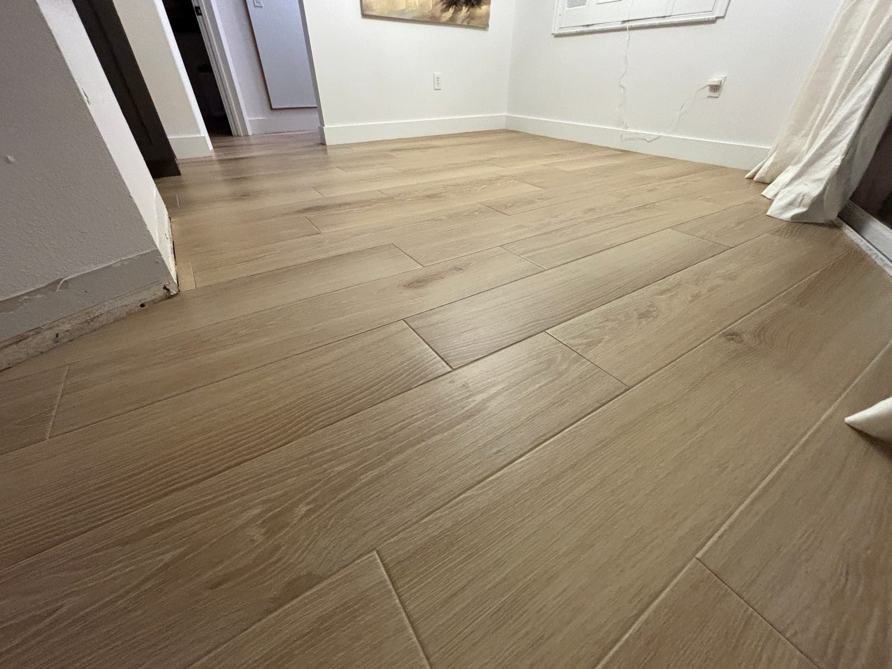 Warm wood-look floor tile installed across a bedroom